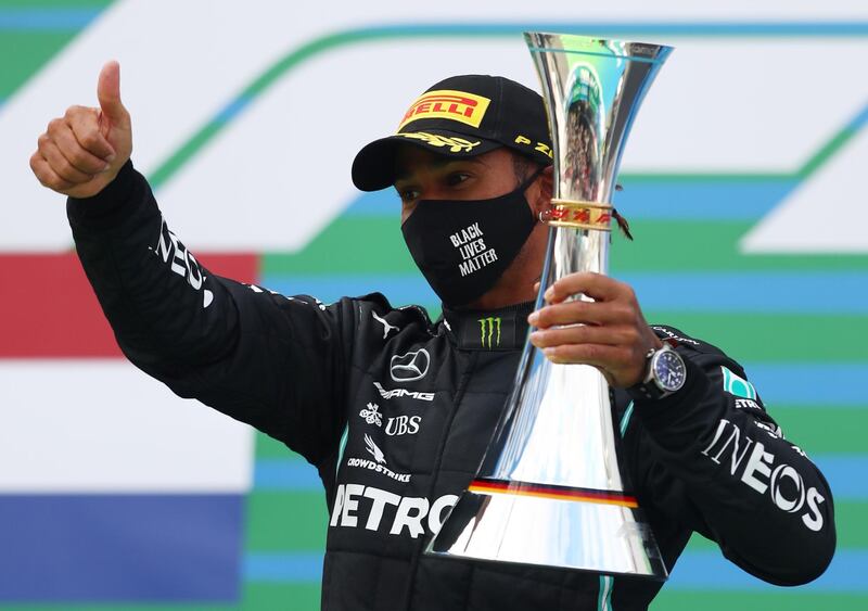 Mercedes' Lewis Hamilton celebrates with a trophy on the podium after winning the race. Reuters