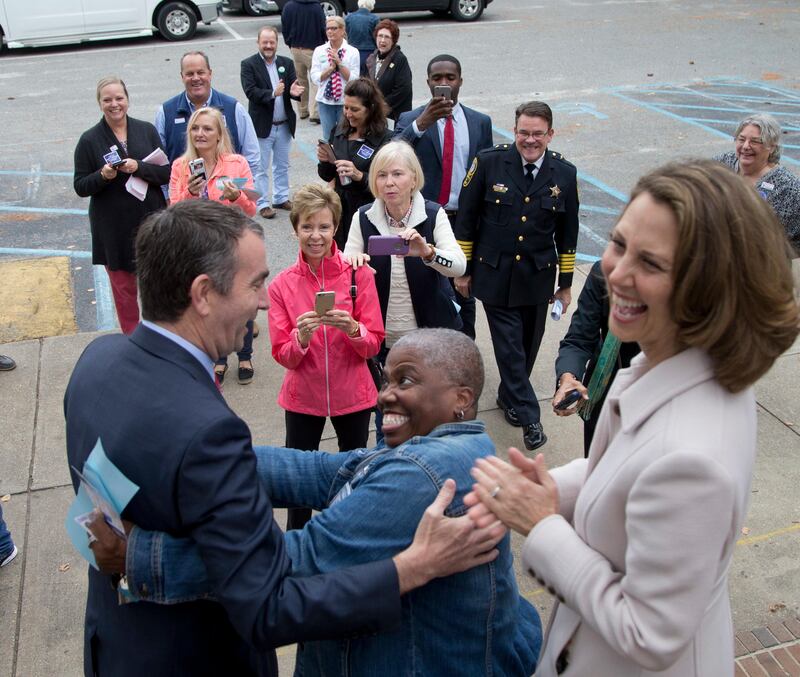 Democratic gubernatorial candidate Lt. Gov. Ralph Northam, left, gets a hug form a supporter as his wife, Pam, right, looks on after voting in Norfolk, Va., Tuesday, Nov. 7, 2017. Northam faces Republican Ed Gillespie in today's election. (AP Photo/Steve Helber)