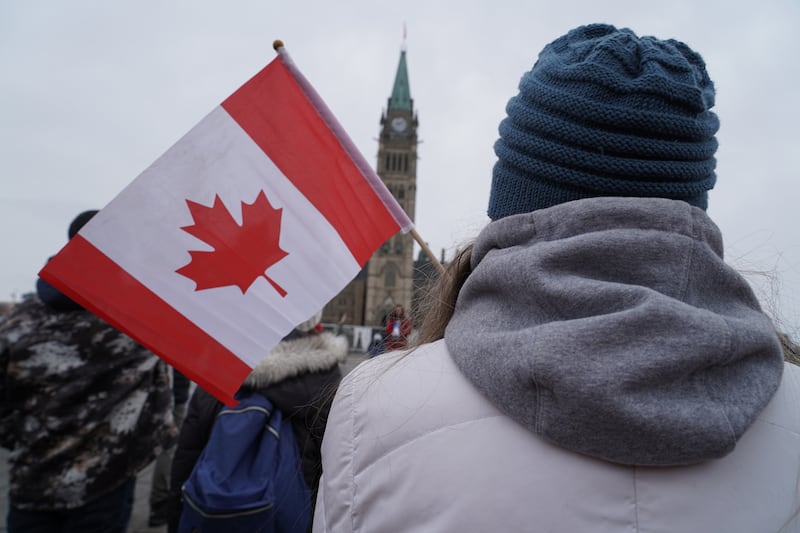 A woman waves a Canadian flag in front of Parliament. Willy Lowry / The National