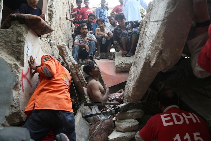 Volunteers try to rescue a trapped resident at the site of the building collapse. Shakil Adil / AP