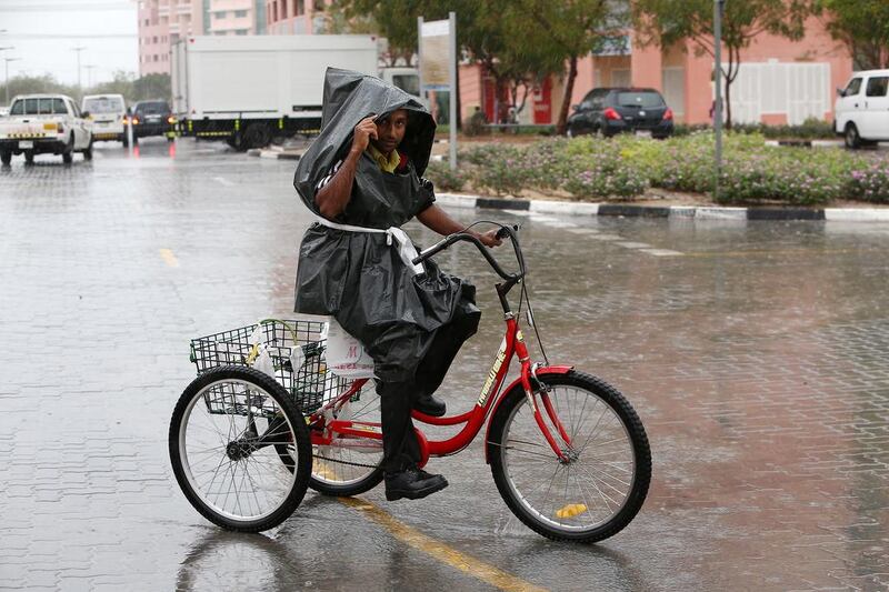 A Discovery Gardens cycle-delivery man adjusts to the rain – something few drivers managed. Pawan Singh / The National