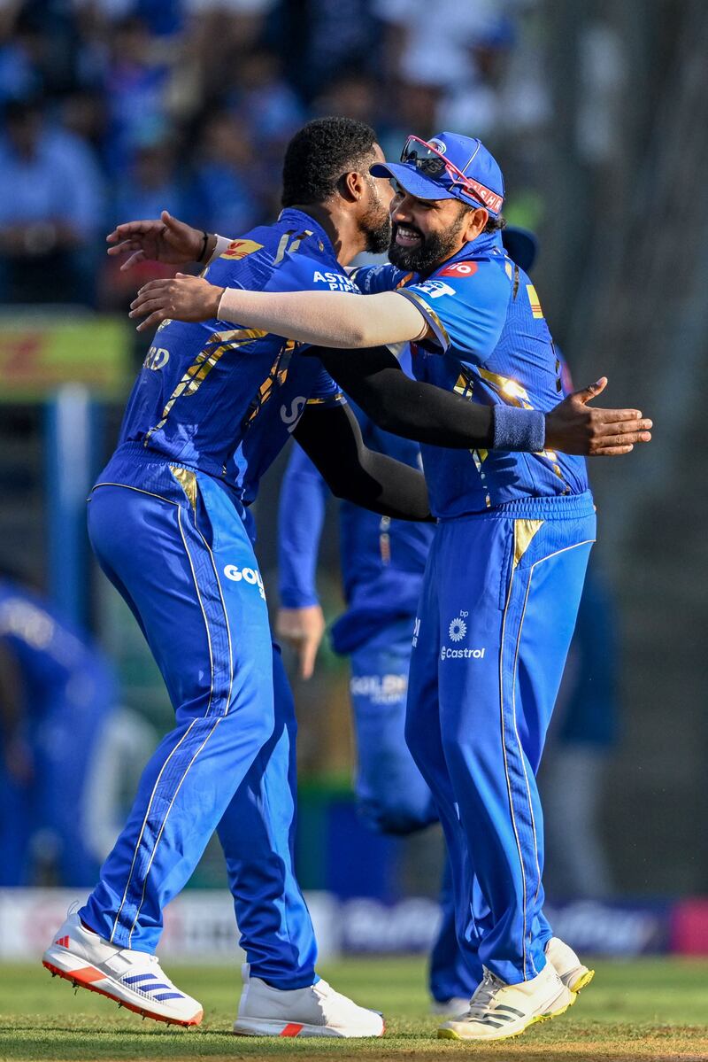 Mumbai Indians' Romario Shepherd celebrates with his teammate Rohit Sharma, right, after taking the wicket of Delhi Capitals' David Warner. AFP