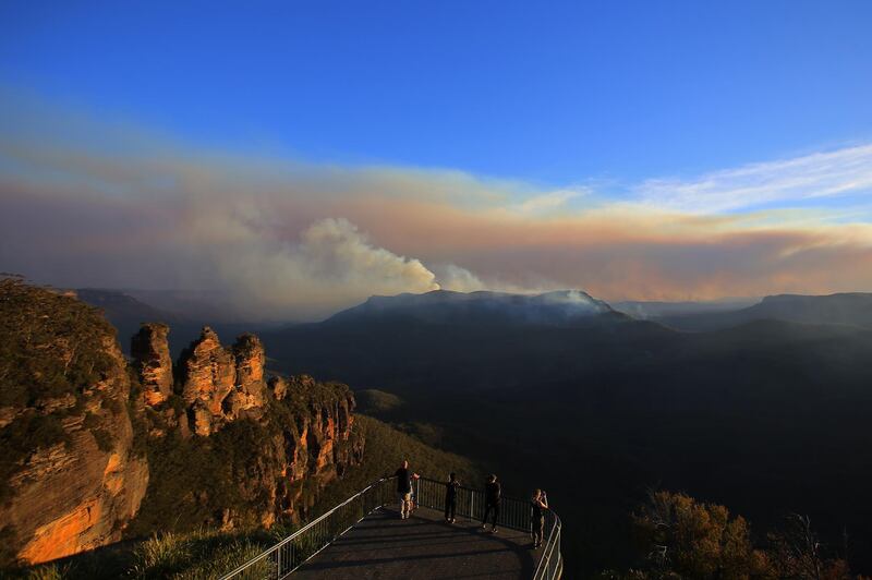 The Three Sisters rock formation is visible as people watch smoke from the Green Wattle Creek fire from Echo Point lookout in Katoomba, New South Wales, Australia.  EPA