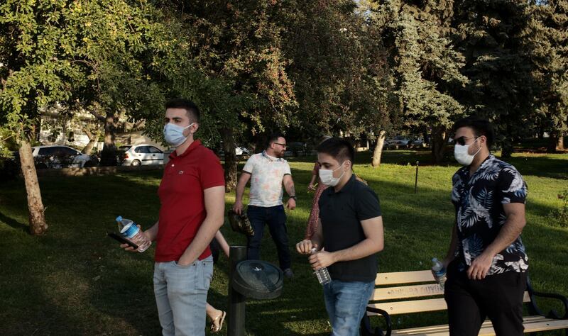 People wearing face masks to protect against the spread of coronavirus, walk in a public garden in Ankara, Turkey. AP Photo
