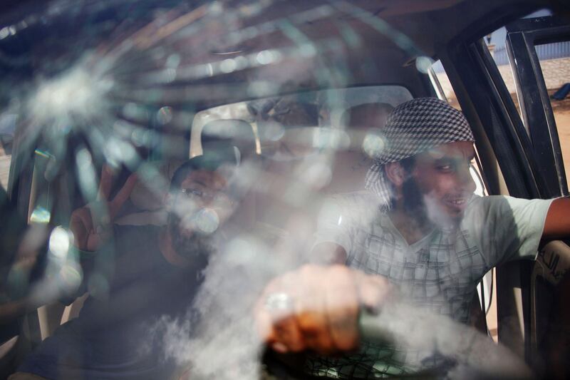 Rebel fighters are seen through a damaged car window at a check point near Sirte, Libya, Tuesday, Sept. 20, 2011. Revolutionary fighters have not been able to take over central positions in Sirte. Pro-Gadhafi forces have the advantage of knowing the city and are heavily armed, making it impossible for the former rebels to stand in at night after advancing during the day. (AP Photo/Manu Brabo)  *** Local Caption ***  APTOPIX Mideast Libya.JPEG-038fc.jpg
