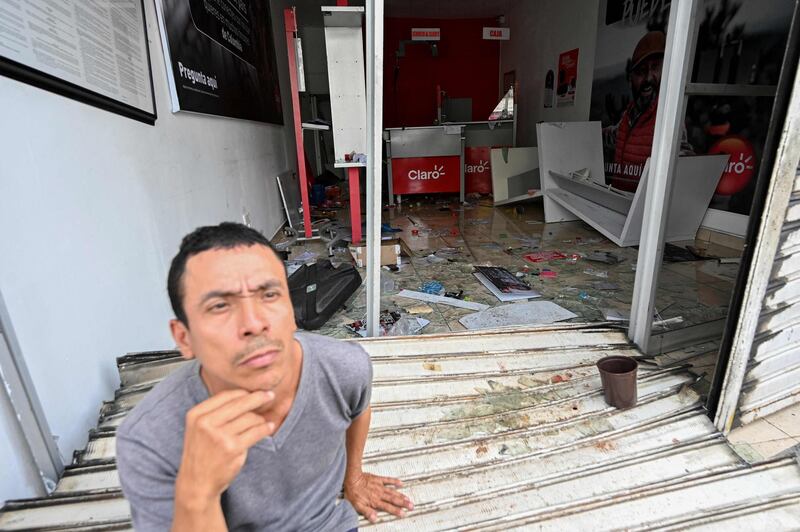 A man sits at the entrance of a store destroyed during clashes between demonstrators and riot police officers in the protests against the government's tax reform in Cali, Colombia, on May 4, 2021. The international community on Tuesday decried what the UN described as an 'excessive use of force' by security officers in Colombia after official data showed 19 people were killed and 846 injured during days of anti-government protests. / AFP / LUIS ROBAYO
