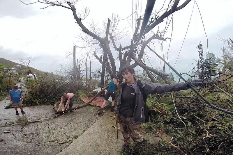 In this image made from video, neighbors clear debris from the road in St. Thomas, U.S. Virgin Islands, Thursday, Sept. 7, 2017. Hurricane Irma weakened slightly Thursday with sustained winds of 175 mph, according to the National Hurricane Center. The storm boasted 185 mph winds for a more than 24-hour period, making it the strongest storm ever recorded in the Atlantic Ocean. The storm was expected to arrive in Cuba by Friday. It could hit the Florida mainland by late Saturday, according to hurricane center models. (AP Photo/Ian Brown)