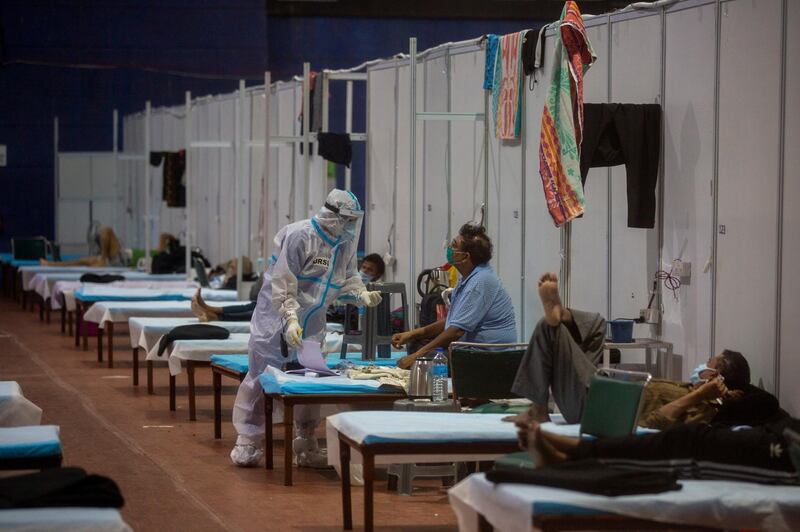 A health worker takes the temperature of a patient at a makeshift Covid-19 care center at an indoor sports stadium in New Delhi. AP Photo