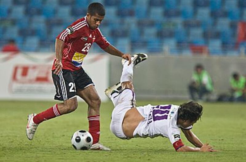 Al Ahli's Ali Hussain, left, sends Al Ain captain Jorge Valdivia flying on Wednesday night.