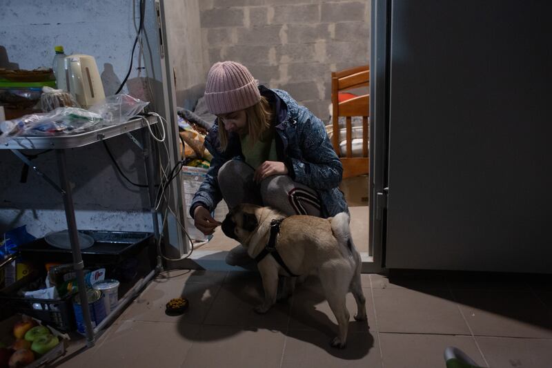 Anna Ponomaryova feeds her dog, Fedya, in the basement under the residential building used as a bomb shelter in Kyiv. Getty