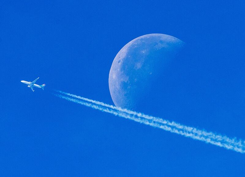 An aircraft passes the setting moon over Frankfurt, Germany. Michael Probst / AP Photo