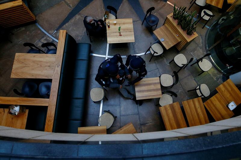Police officers remove a protester from a restaurant in a shopping mall for not wearing a protective mask, during a protest against the government's Covid-19 restrictions in Kassel, Germany. Reuters