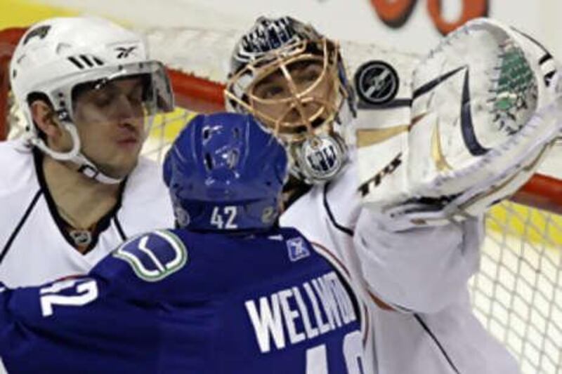 The Edmonton Oilers netminder Dwayne Roloson, right, gloves the puck against Vancouver.