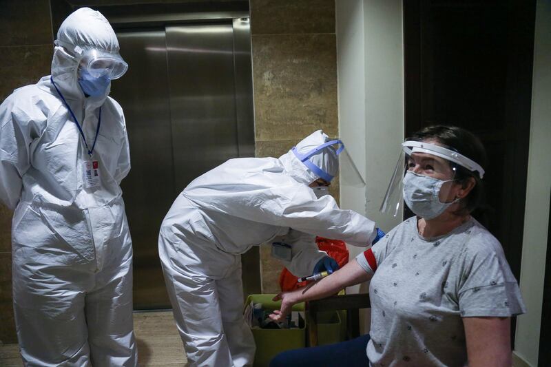 Medical workers in protective gears take blood samples from a woman at her home during a coronavirus antibody testing programme in Ankara, Turkey.  EPA