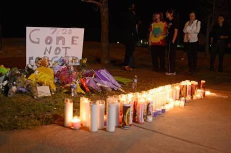 DENVER, CO - JULY 20: People gather at a makeshift memorial for victims of the Century 16 movie theatre where a gunmen attacked movie goers during an early morning screening of the new Batman movie 'The Dark Knight Rises' on July 20, 2012 in Aurora, outside of Denver, Colorado. According to reports, 12 people were killed and 59 wounded when James Holmes allegedly opened fire inside the theater. Police have Holmes 24, of North Aurora, in custody   Kevork Djansezian/Getty Images/AFP== FOR NEWSPAPERS, INTERNET, TELCOS & TELEVISION USE ONLY ==
 *** Local Caption ***  032532-01-09.jpg