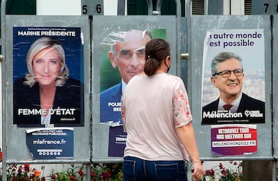 A woman walks past campaign posters for far-right candidates Marine Le Pen and Eric Zemmour and the far-left runner Jean-Luc Melenchon. AP 