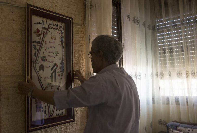 For Mr Al Mahdi, living in view of the Western Wall was a special part of growing up. The wall, sacred to Jews as a remnant of the retaining wall of the Second Jewish Temple, which was destroyed by the Romans in 70AD, is also a religious place for Muslims. Here, he is hanging a framed map of Palestine that consists of tiny embroidery stitches, handmade by his wife. Photo by Heidi Levine for The National