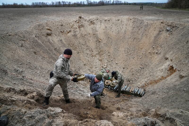 Ukrainian interior ministry soldiers collect explosives in a hole to detonate them near a minefield after battles with Russia at the village of Moshchun close to Kyiv. AP