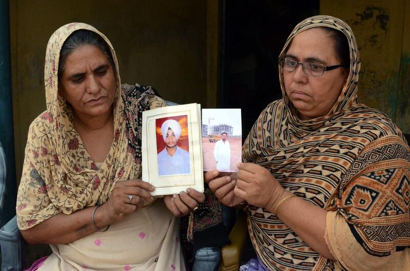 Sukhwinder Kaur, left, and Ranjit Kaur show photographs of their sons Manjinder Singh and Jatinder Singh respectively, who are among 40 Indian workers missing in Iraq, at their village about 30km from Amritsar in India's Punjab state. Raminder Pal Singh / EPA / 18 June, 2014.