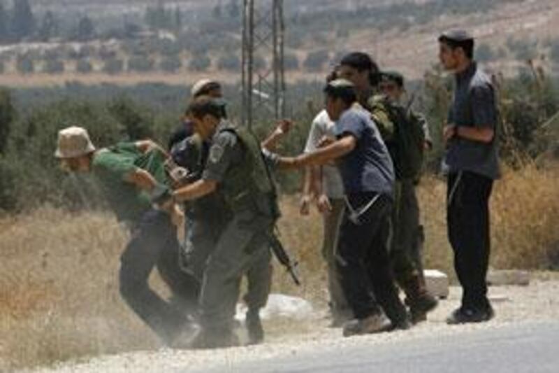 Israeli border police officers detain a Jewish settler after he disrupts Palestinian traffic at the Hawara checkpoint near Nablus.