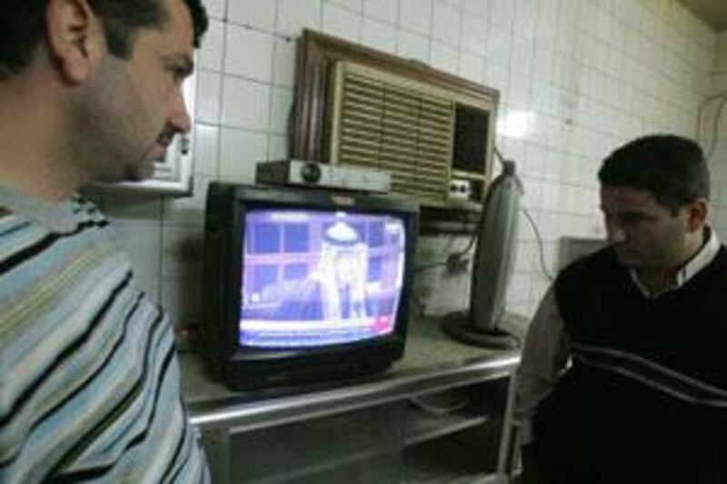 Iraqis watch television as a sentence is passed on Ali Hassan al Majid.