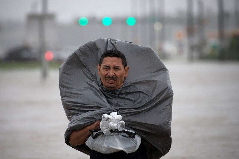 A man uses a bin bag to cover him from the rain while wading through flood waters  in east Houston. Adrees Latif / Reuters