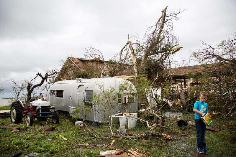 Corey Carpenter, 7, eats crackers in what used to be his cousin's yard that was flooded when Hurricane Harvey hit Bayside, Texas Sunday, Aug. 27, 2017. The Victoria Advocate via AP