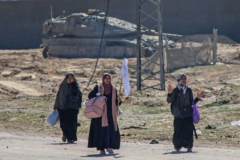 Displaced Palestinians hold a white flag as they pass an Israeli tank position while fleeing the Hamad Town district of Khan Younis. Bloomberg
