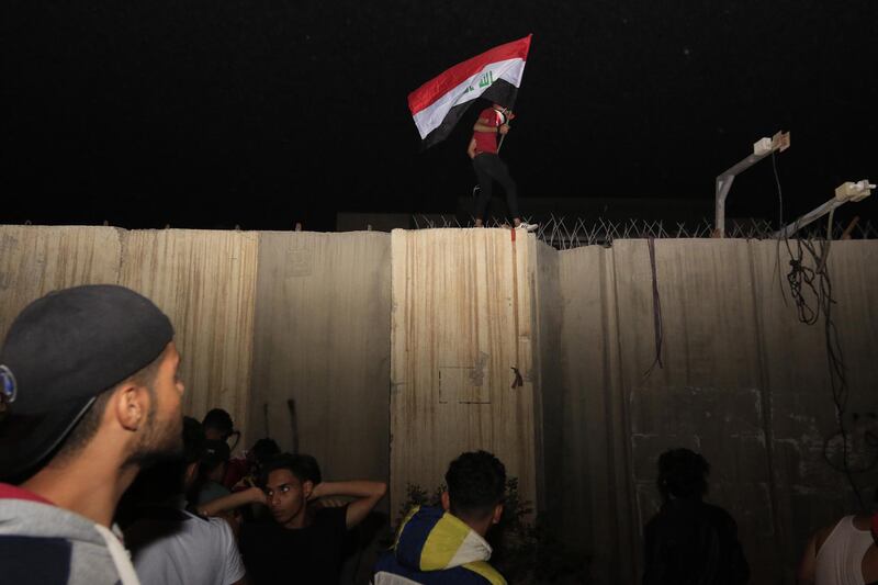 An Iraqi protester waves the Iraqi national flag as he stands on a concrete wall at the Iranian counsulate in Karbala, Iraq, 03 November 2019. EPA