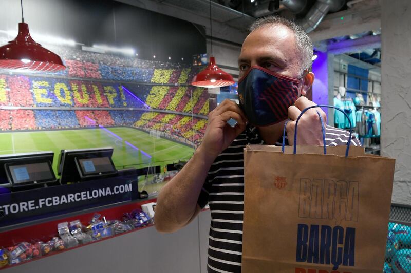 A supporter poses wearing a mask bearing the logo of FC Barcelona after buying it at the FC Barcelona. AFP