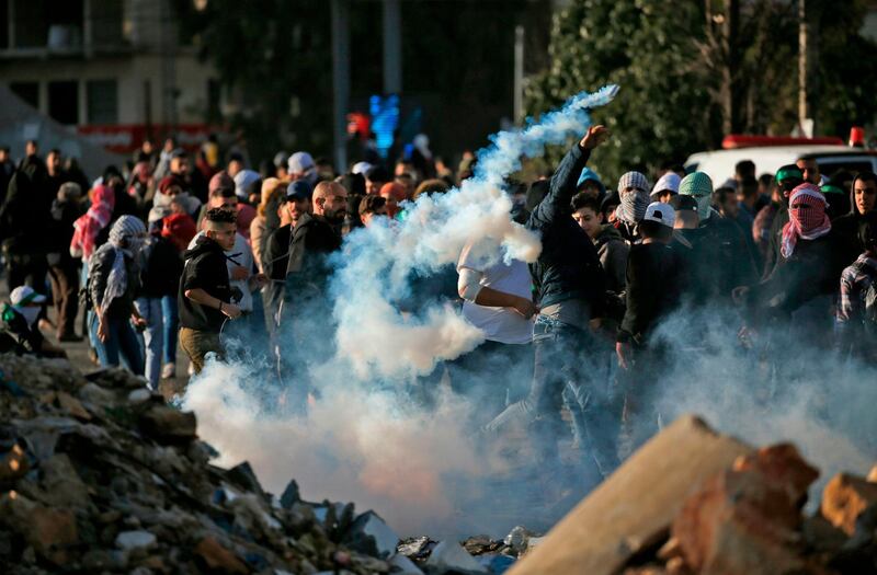 A Palestinian demonstrator throws a tear gas canister back at Israeli soldiers during clashes in Ramallah, near the Jewish settlement of Beit El, in the occupied West Bank on December 13, 2018.    A Palestinian shot dead two Israeli soldiers at a bus stop in the occupied West Bank, the military said, sparking raids in the West Bank city of Ramallah in which one Palestinian was killed. The attack came hours after security forces killed two Palestinian murder suspects, with fears of wider unrest. / AFP / ABBAS MOMANI
