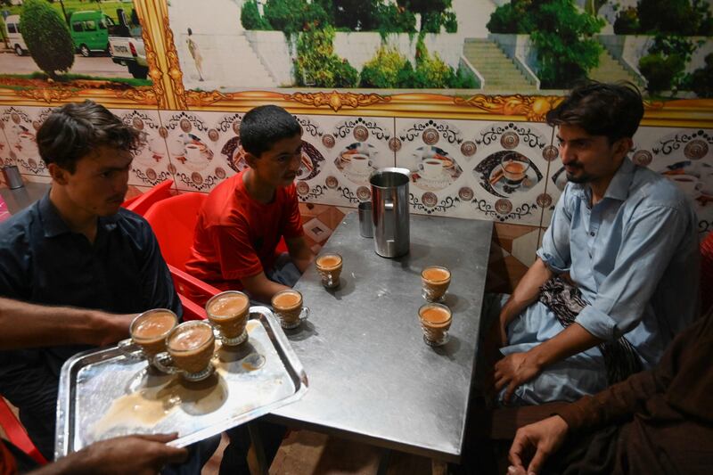 A waiter serves cups of tea to customers at a restaurant in Islamabad. AFP