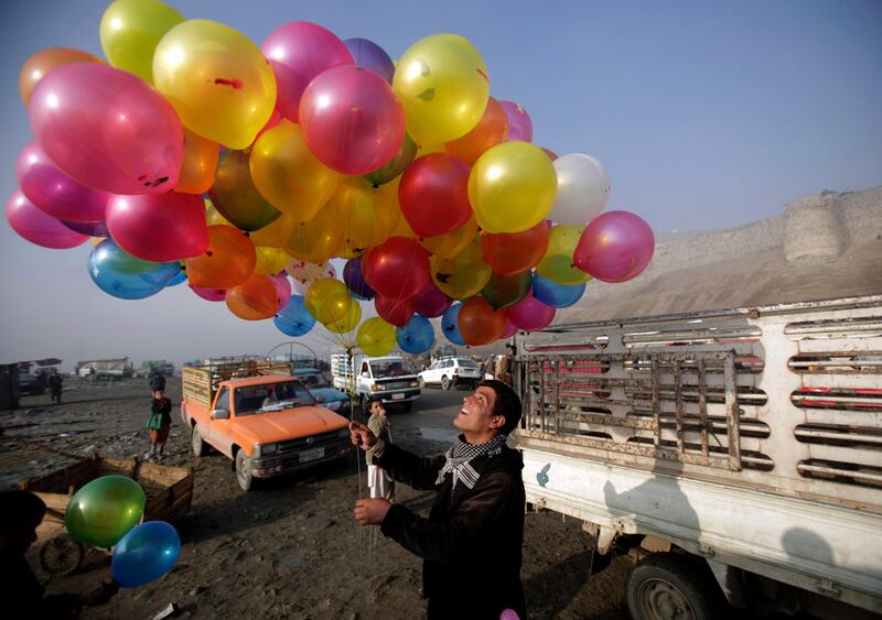 An Afghan youth who sells balloons picks a balloon for a child on a roadside in Kabul, Afghanistan, Friday, Nov. 4, 2011. (AP Photo/Muhammed Muheisen) *** Local Caption ***  APTOPIX Afghanistan Daily Life.JPEG-06c15.jpg