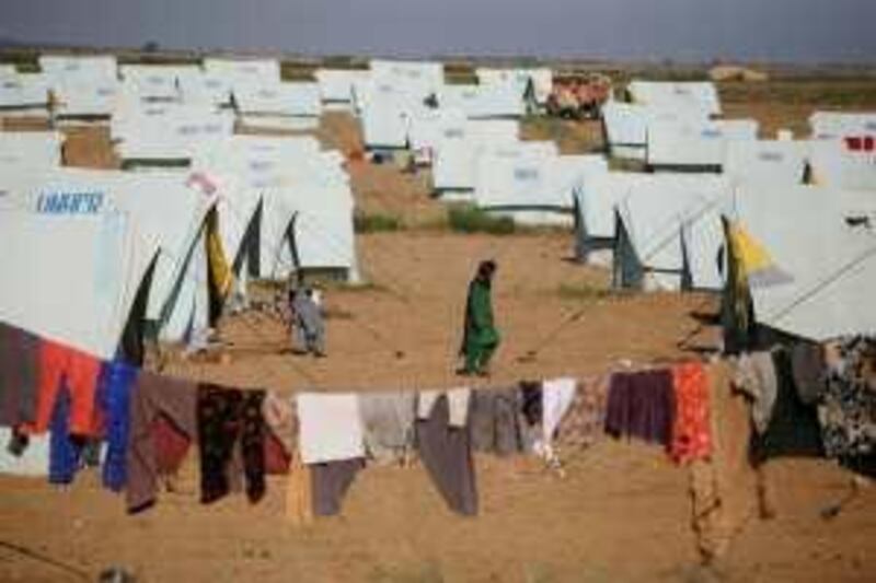 A woman walks past tents at a refugee camp at Swabi, in northwest Pakistan, Sunday, May 10, 2009. Hundreds of thousands have fled fighting between the military and the Taliban in Swat Valley, adding a humanitarian crisis to the nuclear-armed nation's economic, political and other woes. (AP Photo/Greg Baker) *** Local Caption ***  XGB108_APTOPIX_Pakistan.jpg