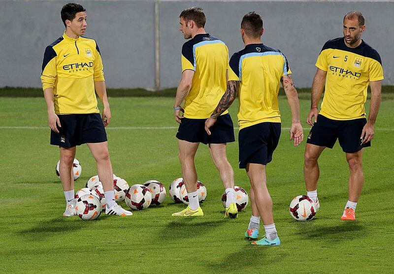 Samir Nasri, left, and James Milner, second left talk during Manchester City's training session in Abu Dhabi on Wednesday. Satish Kumar / The National / May 14, 2014