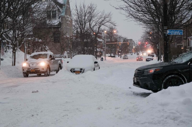 Vehicles make their way along a snow-covered street. AFP