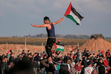 A Palestinian man carries the national flag during a demonstration near the fence along the border with Israel, east of Gaza City. The Palestinian economy faces a "severe fiscal shock" amid Israeli restrictions.  AFP