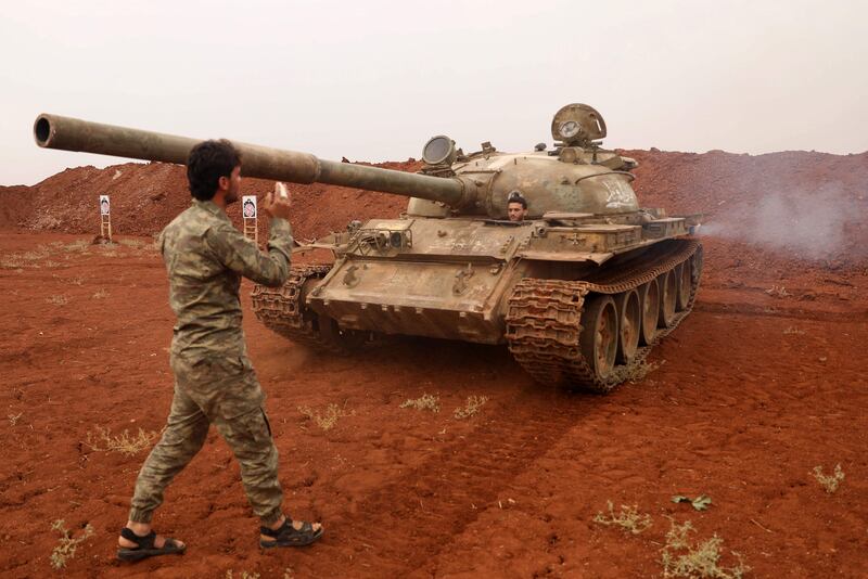 Syrian rebel-fighters from the National Liberation Front (NLF) secure a tank, part of heavy weapons and equipment withdrawn yesterday from a planned buffer zone around Idlib in one of the group's rear positions in a rebel-held area in the southwestern Syrian province on October 9, 2018. The zone is stipulated in a deal by regime ally Russia and rebel backer Turkey to set up a U-shaped buffer zone around Syria's opposition stronghold of Idlib to avert a massive government assault on the area, which would put several million people at risk. The  horseshoe-shaped buffer will separate opposition and government forces and is meant to be free of both heavy weapons and jihadists by October 15.  / AFP / OMAR HAJ KADOUR
