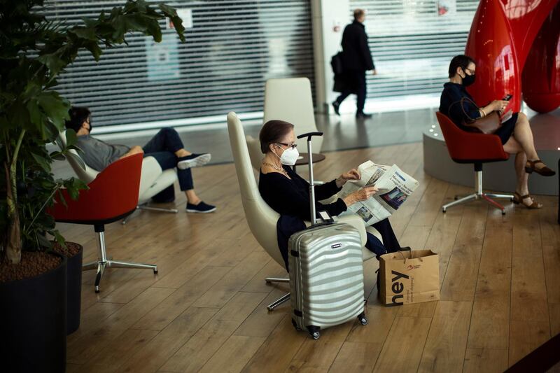 Passengers, wearing face masks to protect against the spread of coronavirus, sit in the waiting area prior to their flight departures, at the Zaventem international airport during the partial lifting of coronavirus COVID-19 lockdown regulations in Brussels, Monday, June 15, 2020. Borders opened up across Europe on Monday after three months of coronavirus closures that began chaotically in March. (AP Photo/Francisco Seco)