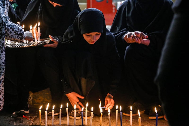 A Shiite Muslim pilgrim lights candles outside the Shrine of Imam Mohammed al-Mahdi during the Shaabaniya ceremony, marking the middle of the Islamic month of Shaban and two weeks before the start of the holy fasting month of Ramadan, and on which Twelver Shiites commemorate the birth of Imam Mahdi (the sect's final Imam), in Iraq's central holy shrine city of Karbala on March 28, 2021.  / AFP / Mohammed SAWAF
