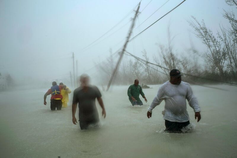 Volunteers walk through a flooded road as they work to rescue families near the Causarina bridge in Freeport, Grand Bahama, Bahamas. AP