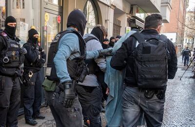 A man is led away by police with a blanket over his head during a raid in Berlin, Germany, Thursday, Feb. 18, 2021. Police cracked down on clan crime in Berlin and the surrounding area with a major raid on Thursday morning. (Christophe Gateau/dpa via AP)