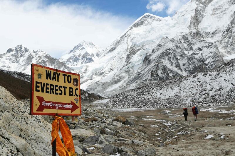 A sign points towards the Everest base camp while two  trekkers walk in the Everest region in Solukhumbu district some 140km northeast of Nepal's capital Kathmandu. Prakash Mathema / AFP
