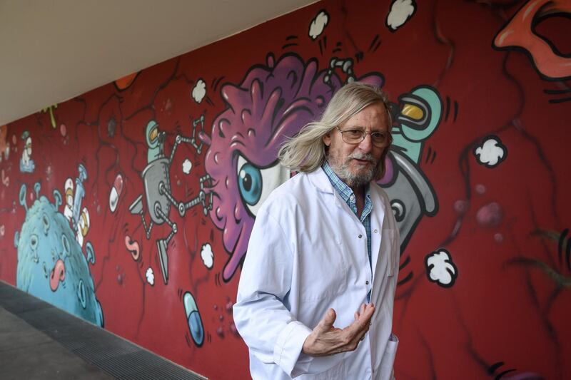 French medecine professor Didier Raoult walks along a wall painted by graffitti artist Jace at his IHU medical institute in Marseille where his works have been at the forefront of promoting hydroxychloroquine as a potential treatment for Covid-19 and has also been subject to criticisms over methodology.  AFP