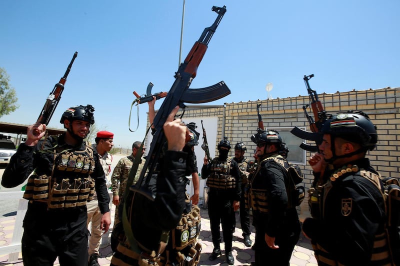 Members of Iraqi Popular Mobilization Forces (PMF) carry their weapons as they shout slogans at their headquarters in the holy city of Najaf, Iraq July 2, 2019. REUTERS/Alaa Al-Marjani