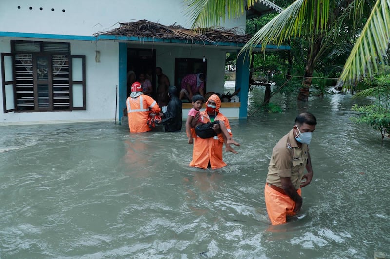 Police and rescue workers evacuate a flooded house in a coastal area of Kochi after Cyclone Tauktae caused heavy rain. AFP