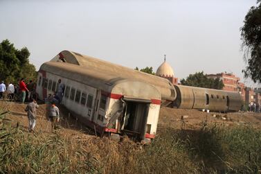 People gather at the site where train carriages derailed in Qalioubia province, north of Cairo, Egypt April 18, 2021. Reuters