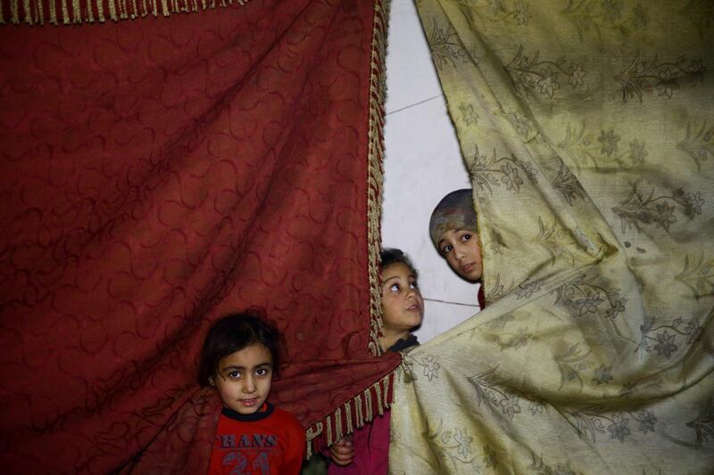 Children peep out from behind curtains in a shelter in Douma on March 11, 2018. Bassam Khabieh / Reuters