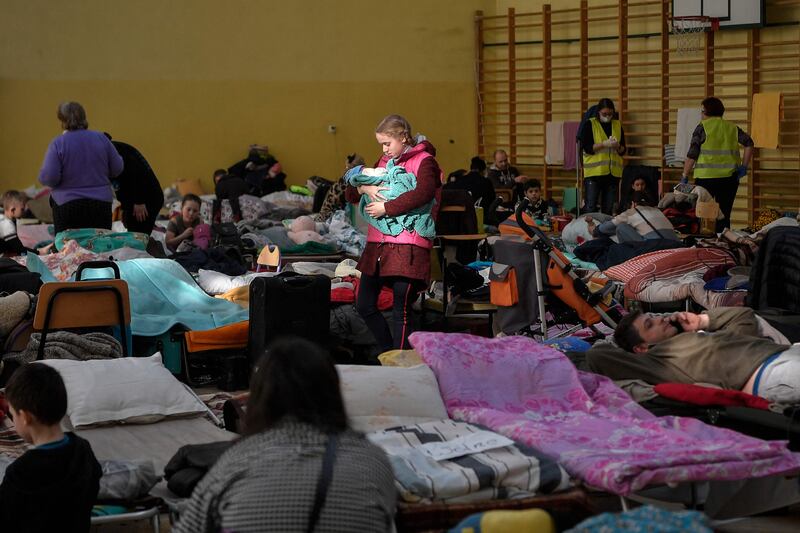 A girl holds her infant sibling at a temporary shelter for Ukrainian refugees in Przemysl, Poland. AFP