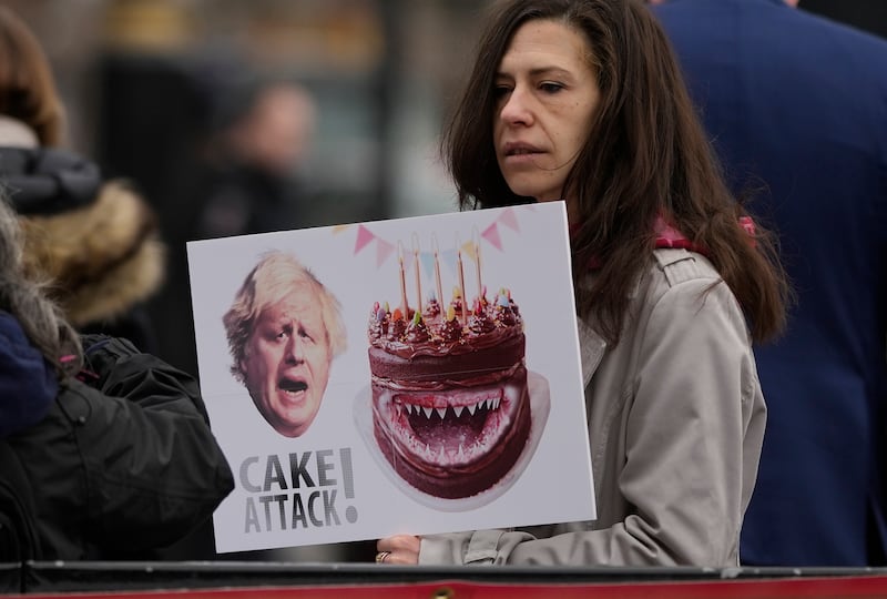 An anti-Boris Johnson demonstrator holds a placard bearing an image of Britain's Prime Minister Boris Johnson and a cake, near the Houses of Parliament, in London, on February 2. AP